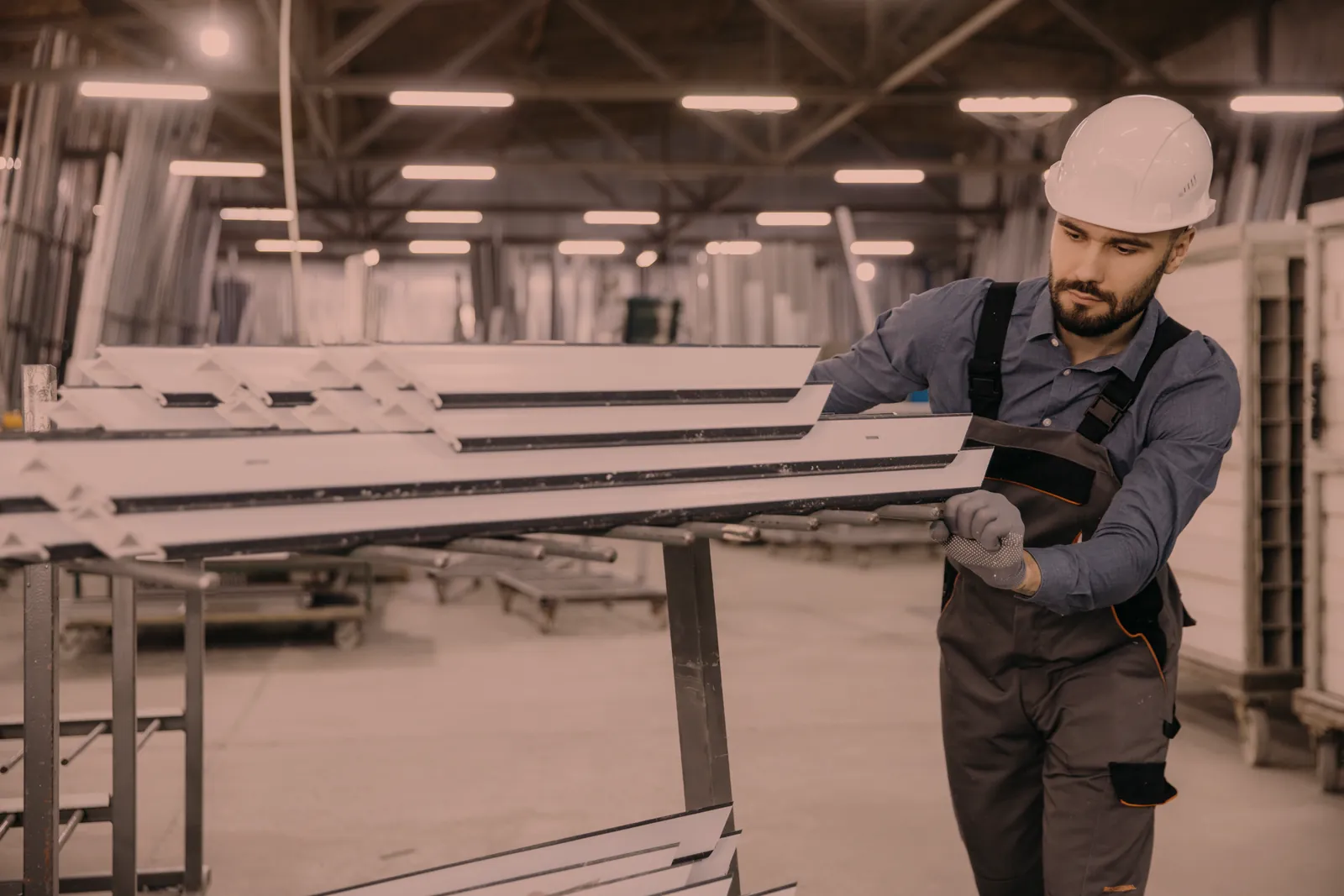 Worker handling cut aluminum extrusions on a shop cart, aluminum cutting, forming, and assembly by O'Donnell Metal Fab