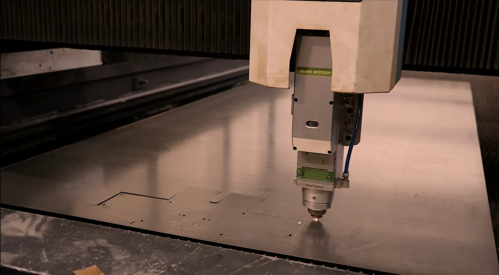 CNC laser cutting head over a steel sheet with parts already cut, laser cutting service at O'Donnell Metal Fab in Norristown PA