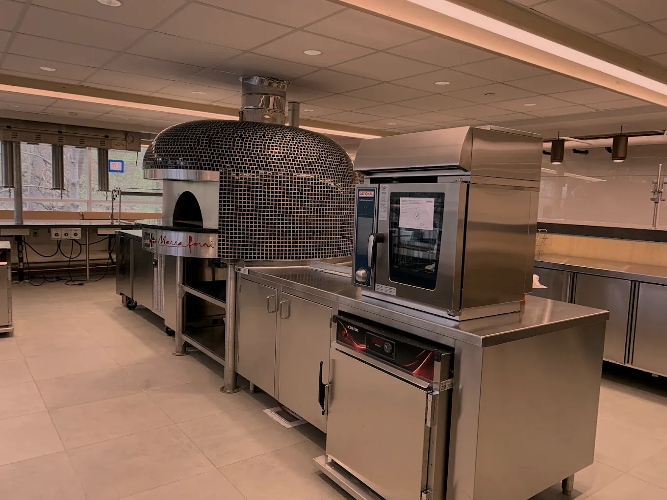 Stainless steel kitchen counters and cabinets installed beside a pizza oven by the O'Donnell Metal Fab mobile welding team