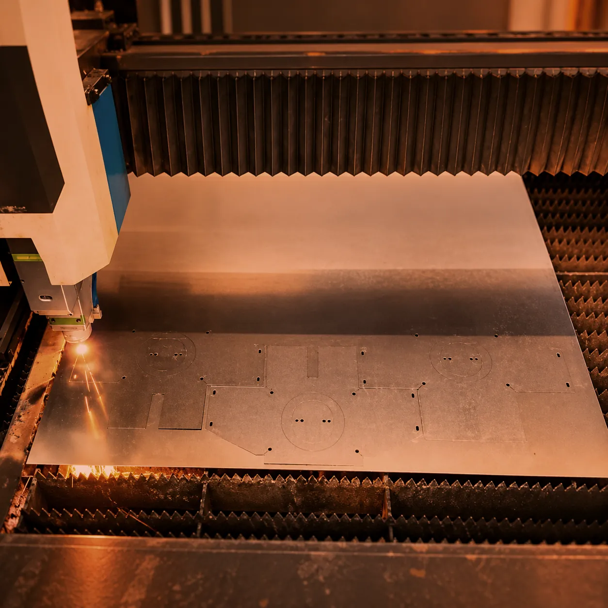 Fiber laser cutting parts from a steel sheet with sparks at the cut, custom metal fabrication at O'Donnell Metal Fab in Norristown PA