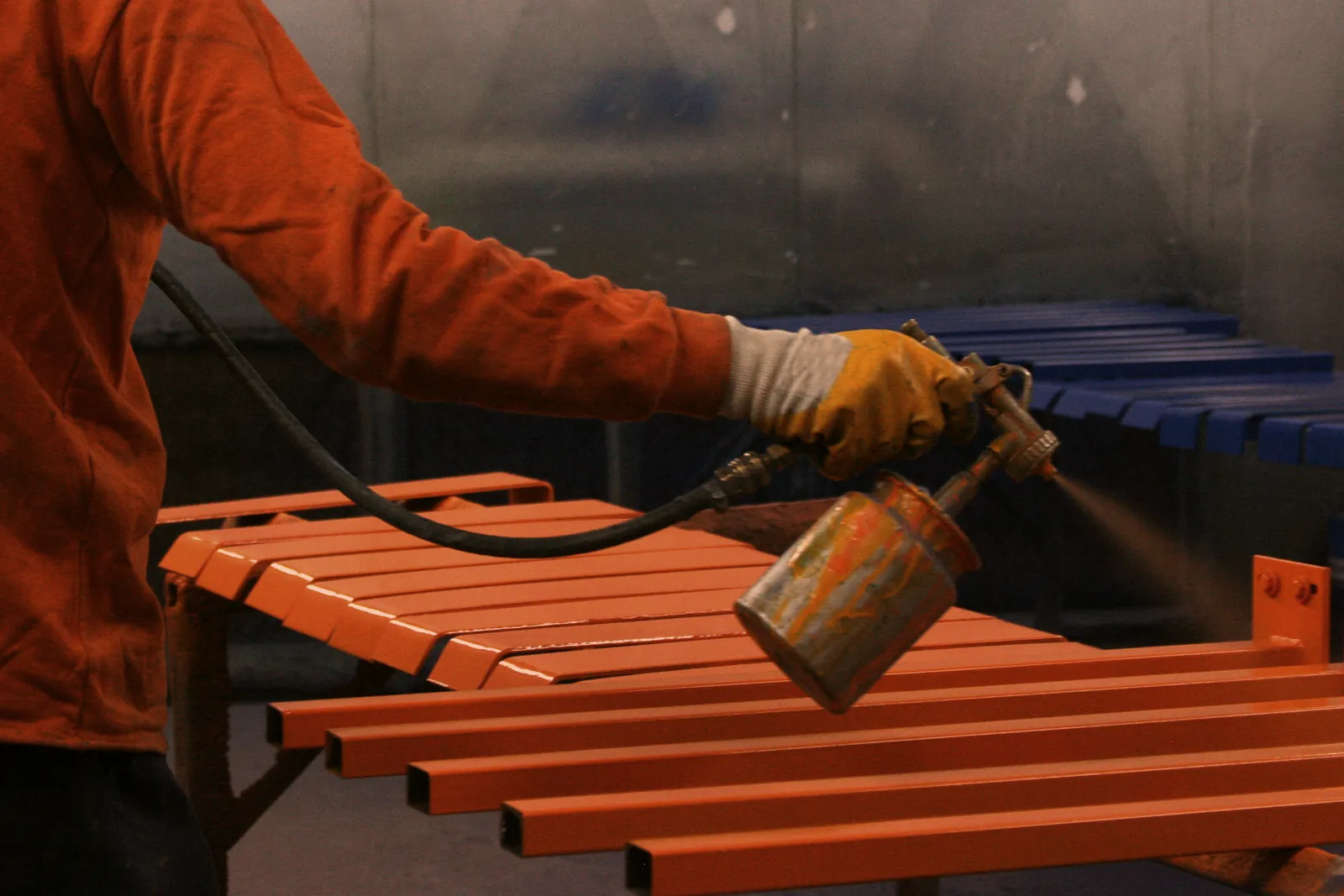 Powder coating steel bars to an orange finish in the spray booth, powder coating and finishing service at O'Donnell Metal Fab in Norristown PA